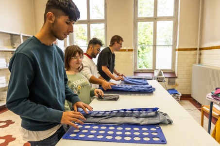 Schüler*innen falten Wäsche mithilfe des Wäschefaltbretts