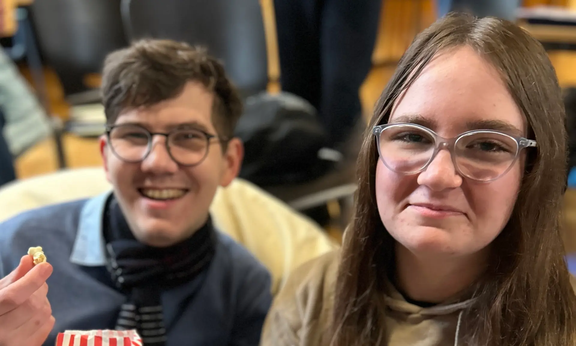 Eine Schülerin und ein Schüler sitzen im Sitzsack, lächeln und haben beide eine Tüte mit Popcorn in der Hand.