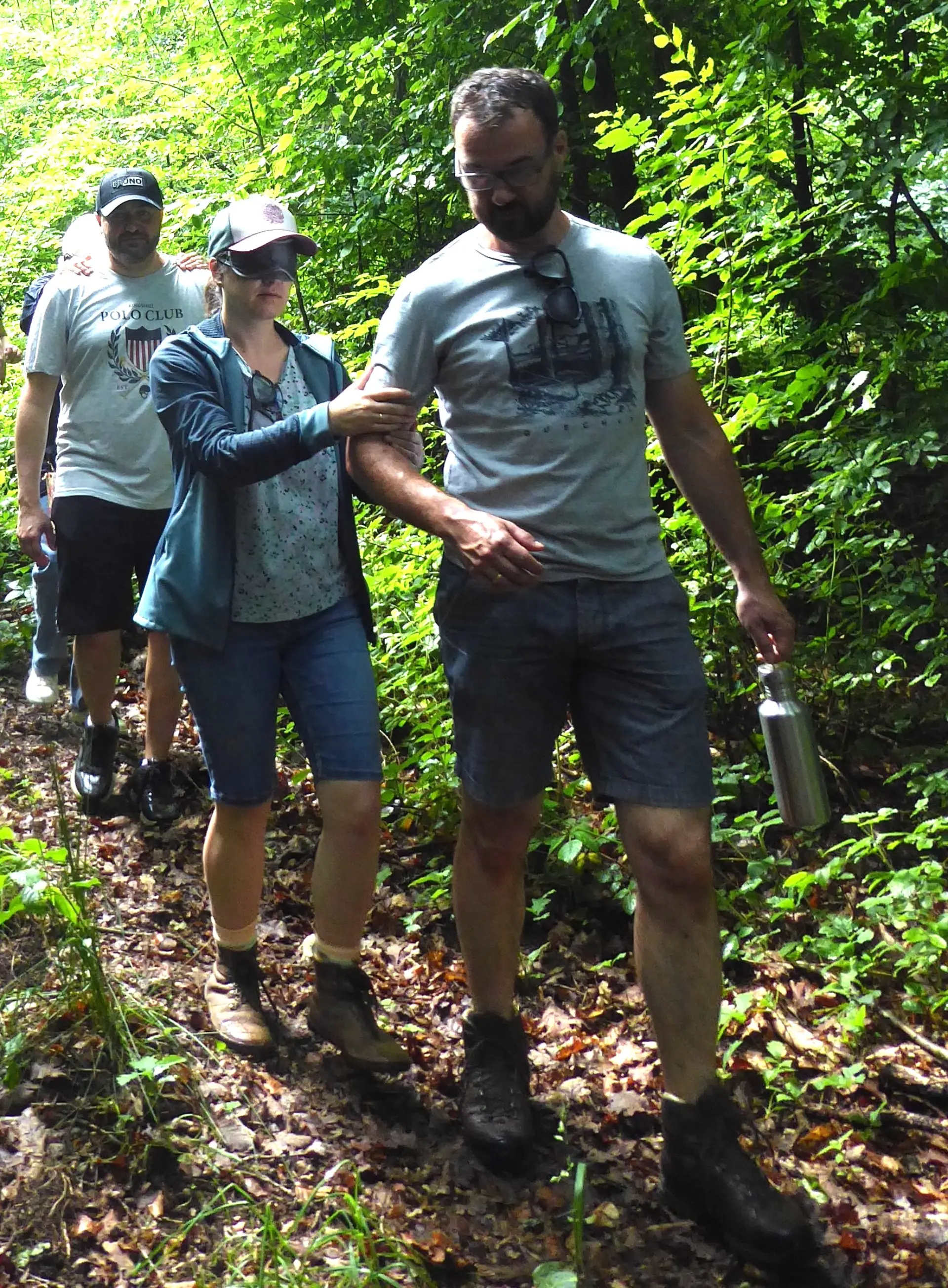 Ein Elternteil wir unter der Augenmaske durch den Wald geführt.