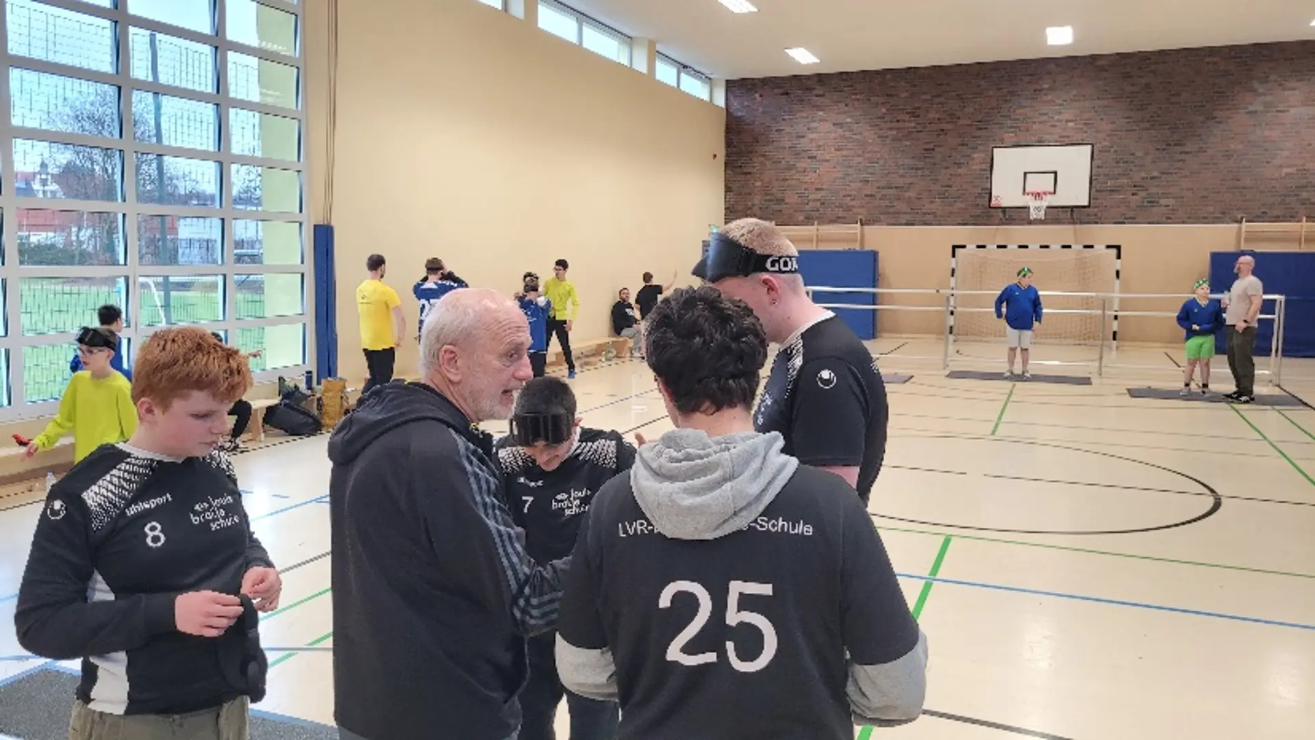 Ein Lehrer steht mit einer Gruppe von Spielern vor dem Tor.