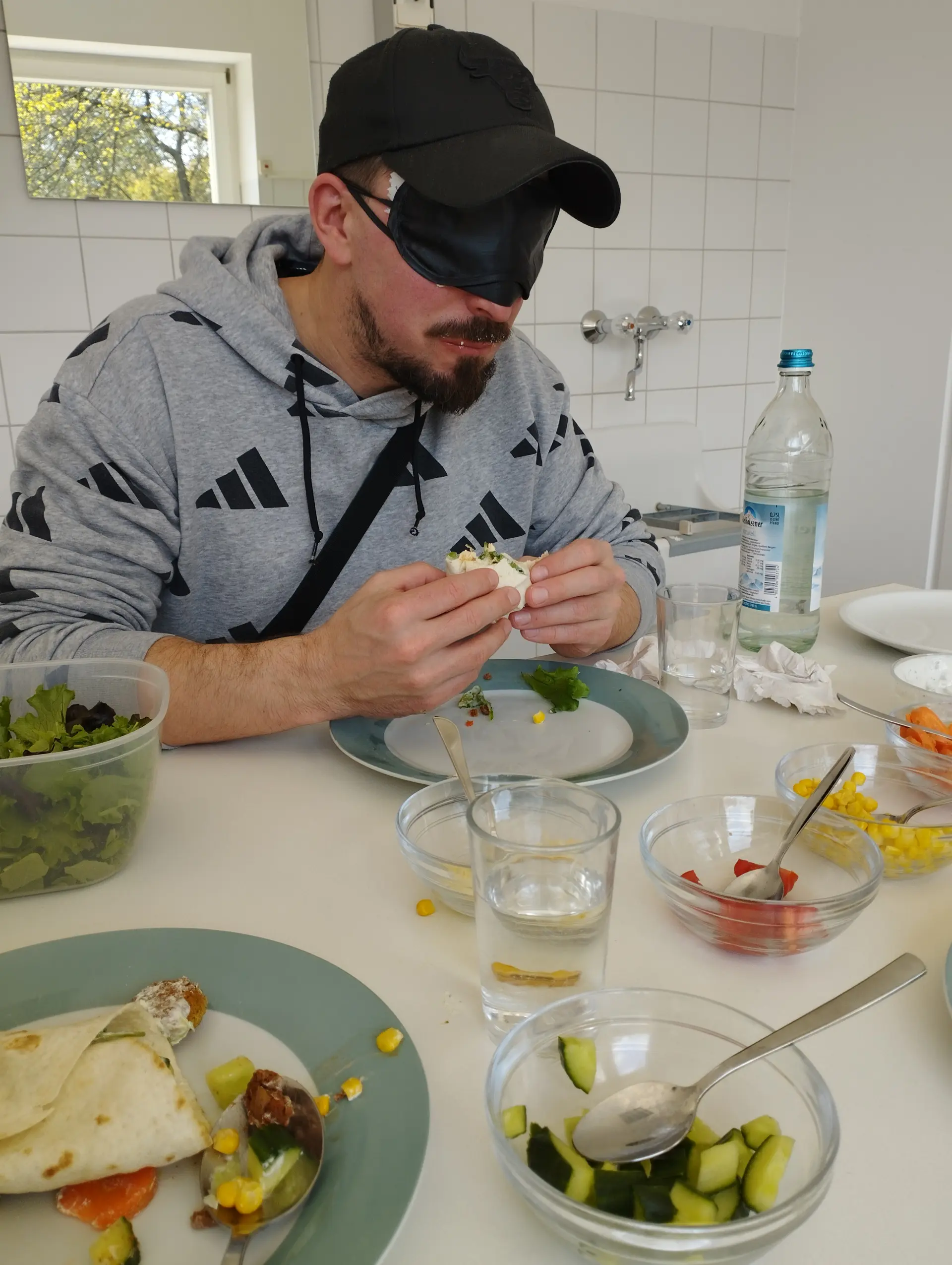 Ein Schüler sitzt mit Augenbinde am Tisch und ist seinen Wrap.