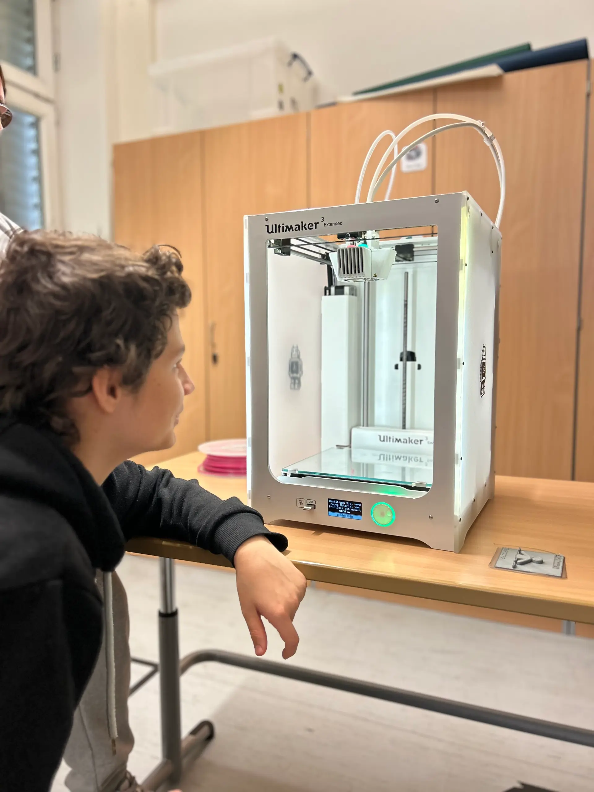 Ein Schüler sitzt vor dem 3D-Drucker
